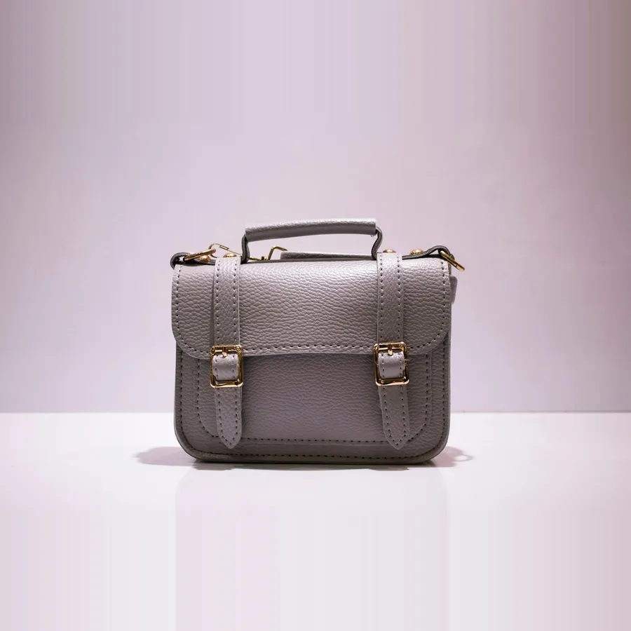 Grey leather satchel on a lilac backdrop with a reflection